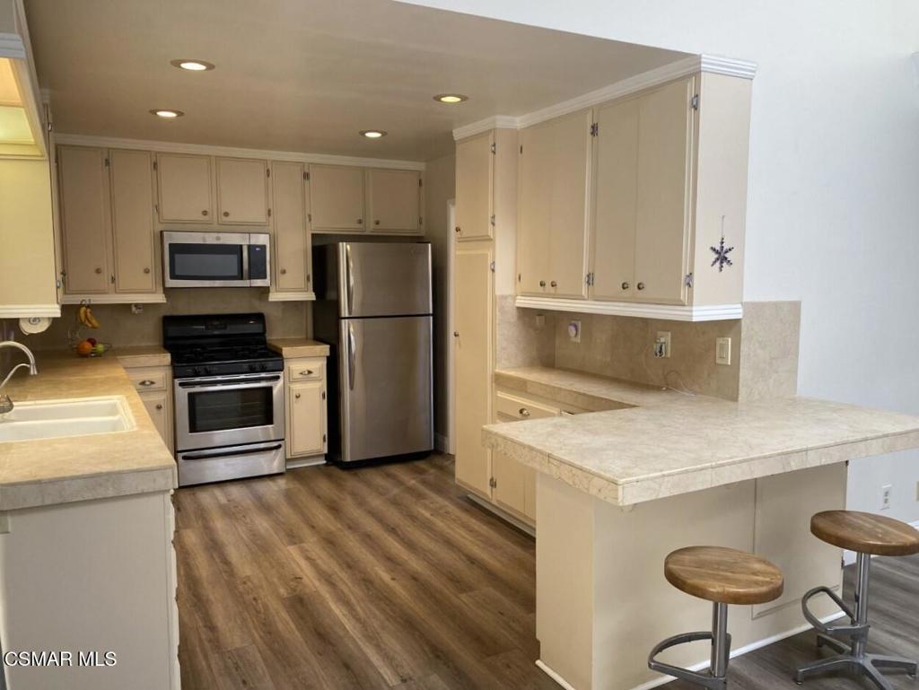652 Harper Street Simi Valley, CA 93065 - Photo 5 of 27 a kitchen with a refrigerator a stove and a microwave oven with wooden floor