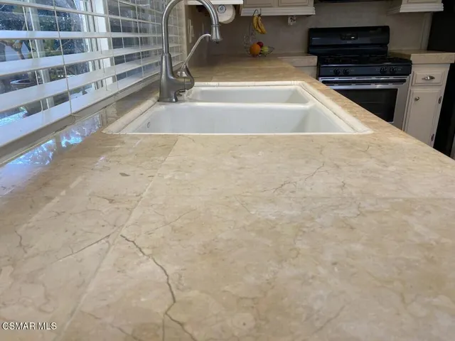 a view of kitchen with granite countertop a sink and a stove