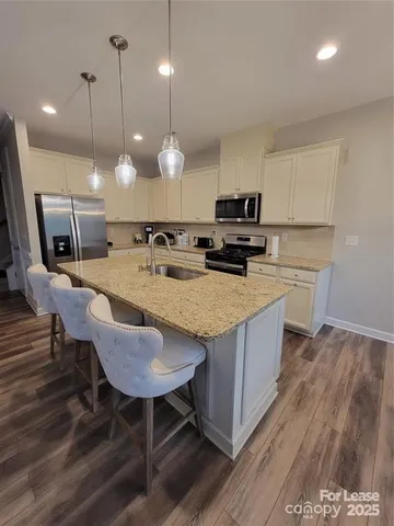 a kitchen with a sink a microwave a stove and chairs