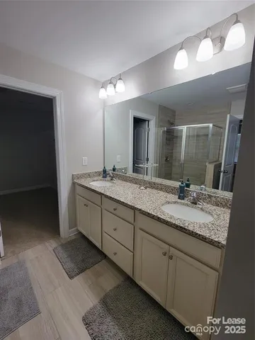 a bathroom with a granite countertop double vanity sink and a mirror