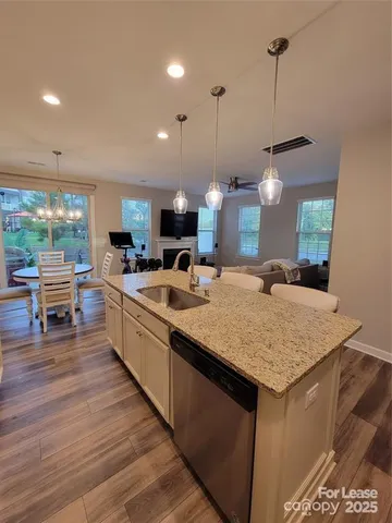 a large kitchen with kitchen island a stove a sink a center island and wooden floor