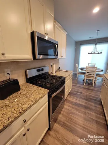a kitchen with stainless steel appliances granite countertop a stove a sink and a microwave