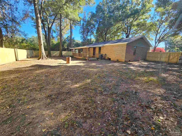 a view of backyard with large trees and wooden fence