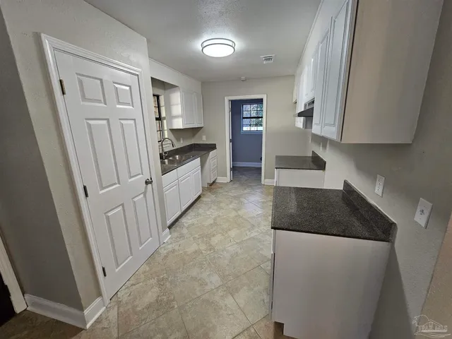 a kitchen with granite countertop white cabinets and refrigerator