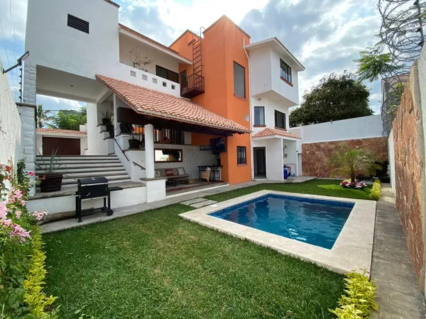 a view of a house with pool fire pit and chairs in a patio