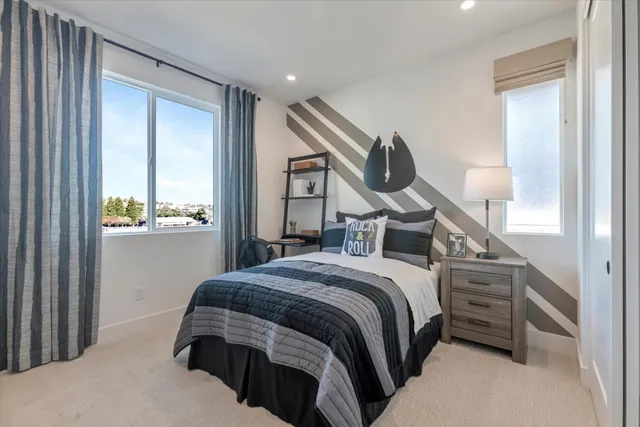 a bedroom with a bed a mirror on the dresser and a window