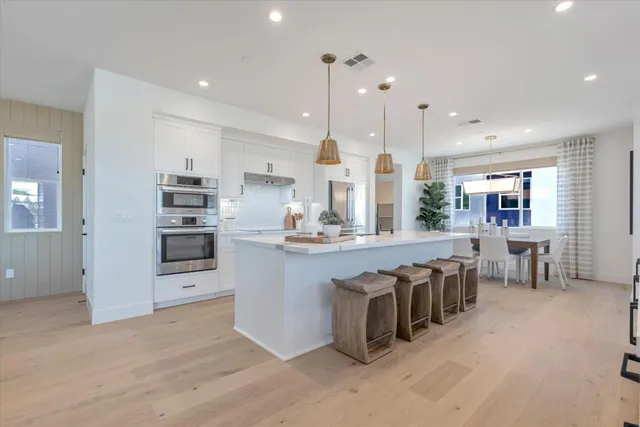 a large kitchen with stainless steel appliances kitchen island granite countertop a large kitchen island a stove a refrigerator a sink and a dining table with the view of kitchen