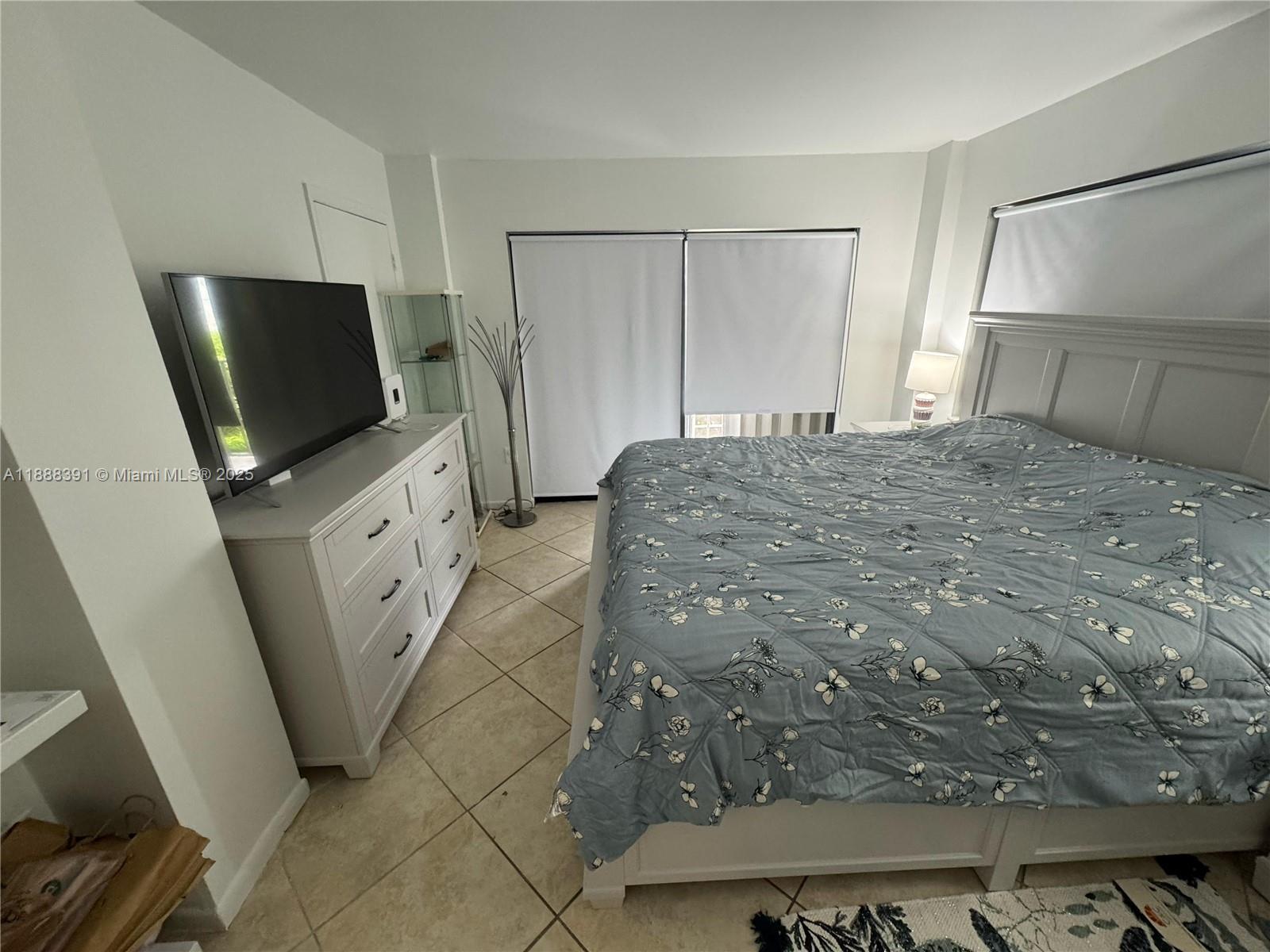 8255 Abbott Avenue, Unit 402 Miami Beach, FL 33141 - Photo 27 of 32 a bedroom with a bed and a flat screen tv