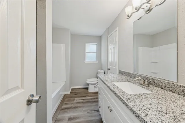 a spacious bathroom with a granite countertop sink a mirror and a shower