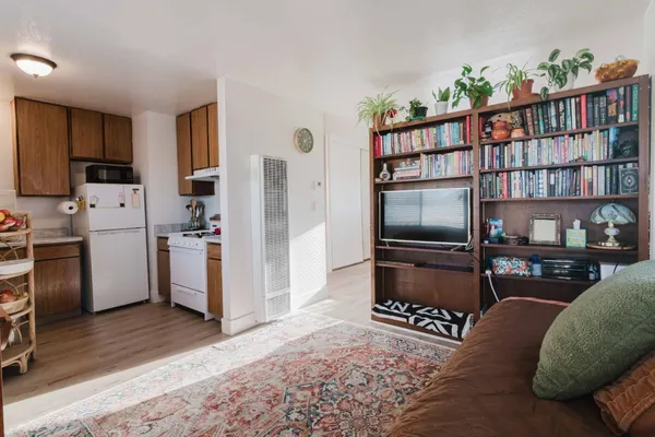 a living room with stainless steel appliances furniture a refrigerator and a bookshelf