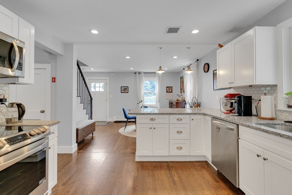 103 Stimson Street Boston, MA 02132 - Photo 5 of 10 a large kitchen with cabinets wooden floor and stainless steel appliances