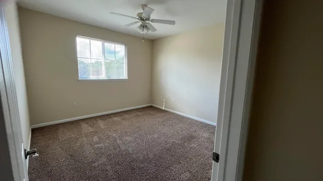 an empty room with windows and fan
