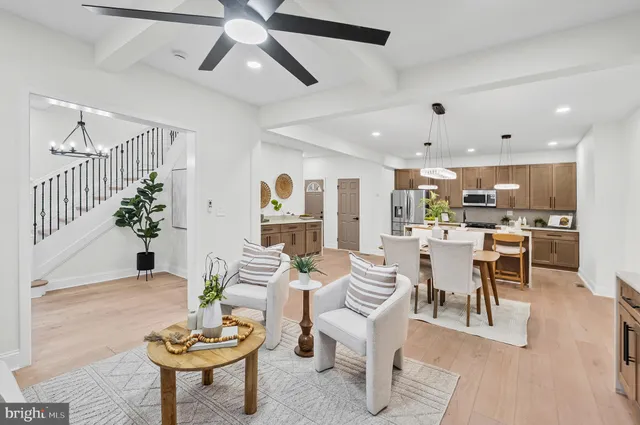 a living room with furniture kitchen view and a chandelier
