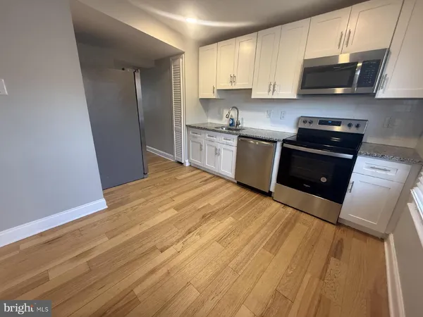 a kitchen with granite countertop wooden floors stainless steel appliances and sink