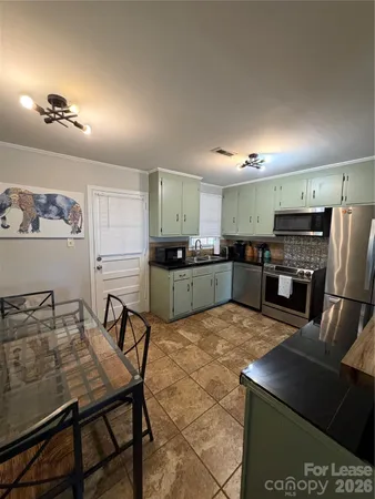 a kitchen with stainless steel appliances granite countertop a table chairs sink refrigerator and microwave