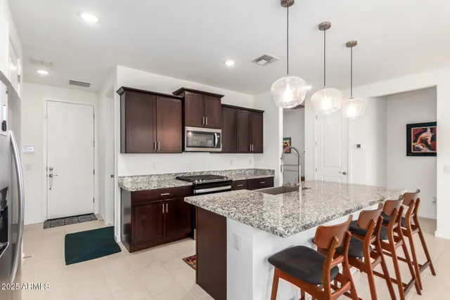 a kitchen with stainless steel appliances granite countertop a stove top oven a sink and a refrigerator