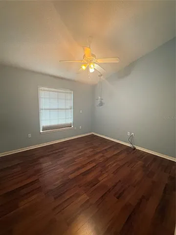 a view of empty room with wooden floor and fan