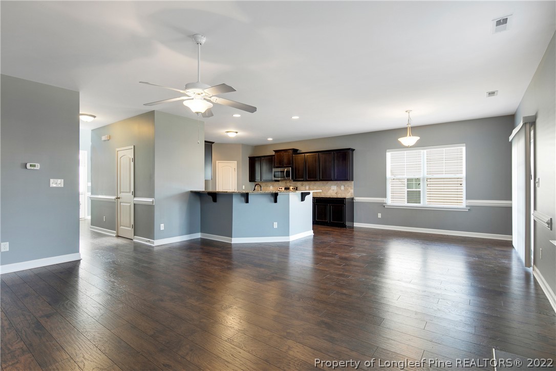 826 Harry Truman Road Fayetteville, NC 28311 - Photo 9 of 48 an empty room with wooden floor kitchen view and a kitchen