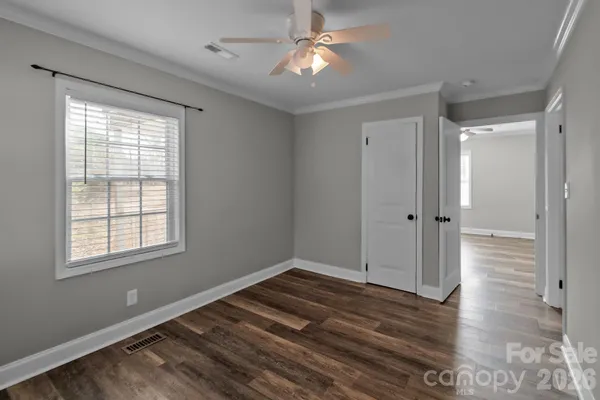 a view of empty room with wooden floor and fan
