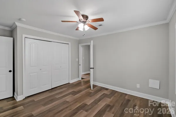 a view of an empty room with wooden floor and a ceiling fan