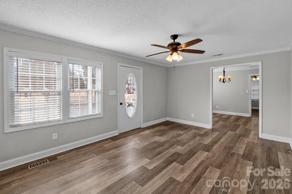 a view of an empty room with window and wooden floor