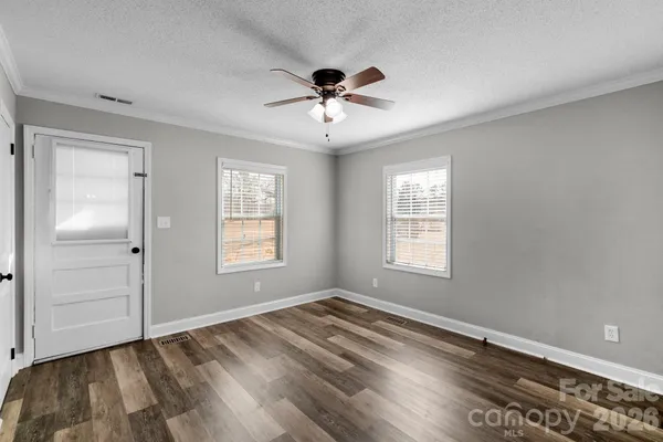 a view of an empty room with window and wooden floor