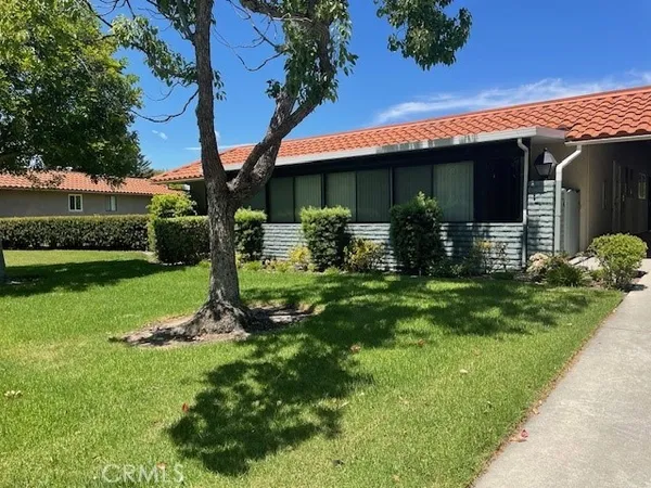 a view of a house with a yard and a large tree