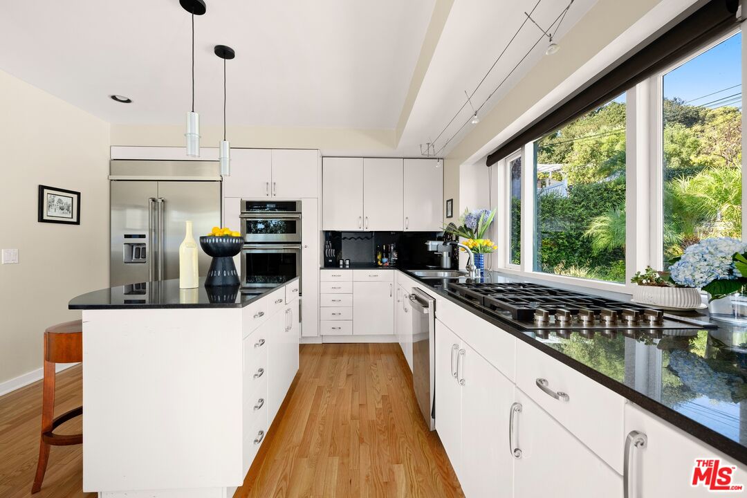 680 Glenmore Boulevard Glendale, CA 91206 - Photo 9 of 15 a kitchen with stainless steel appliances kitchen island granite countertop a stove a sink and white cabinets with wooden floor