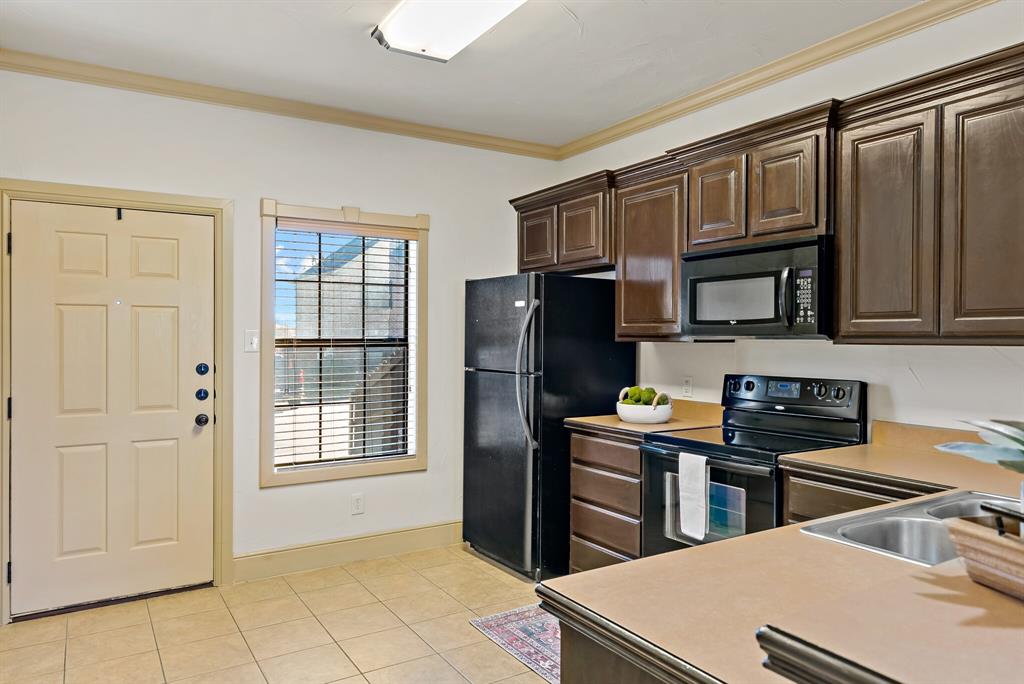11118 Marion Road, Unit 105 Sanger, TX 76266 - Photo 10 of 29 Kitchen featuring dark wood-finish cabinetry, black appliances, and a double basin sink