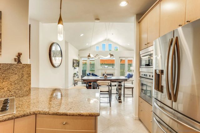 a kitchen with stainless steel appliances granite countertop a refrigerator a oven a sink and a dining table with wooden floor