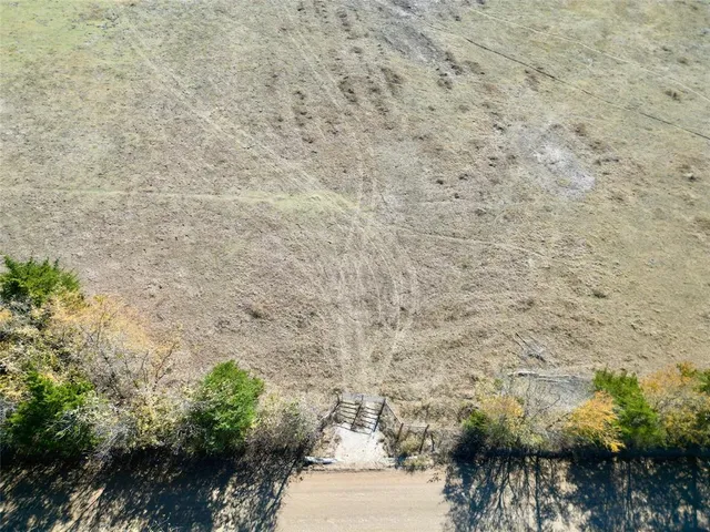 a view of a dry field with trees in background