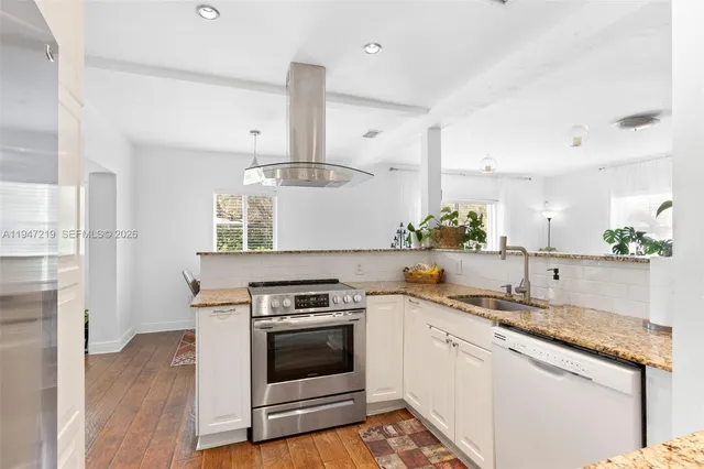 a kitchen with stainless steel appliances granite countertop a sink a stove and a wooden floors