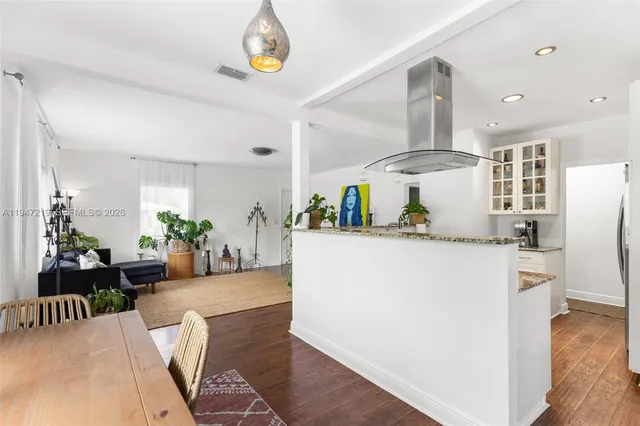 a kitchen with stainless steel appliances a refrigerator a sink dishwasher a oven a dining table and chairs with wooden floor