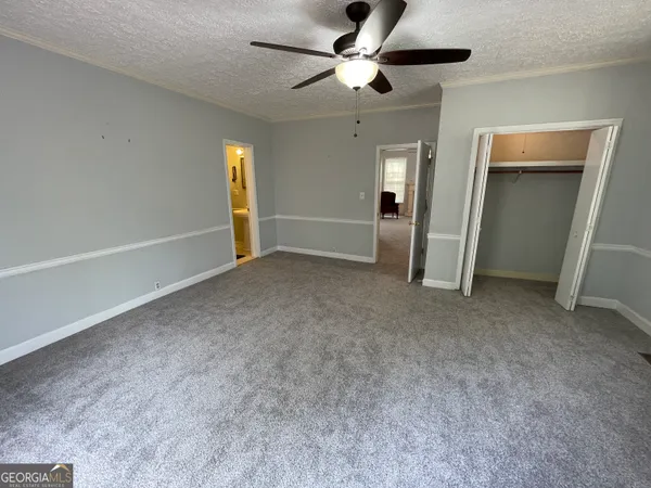 a view of a livingroom with a fireplace a ceiling fan and windows