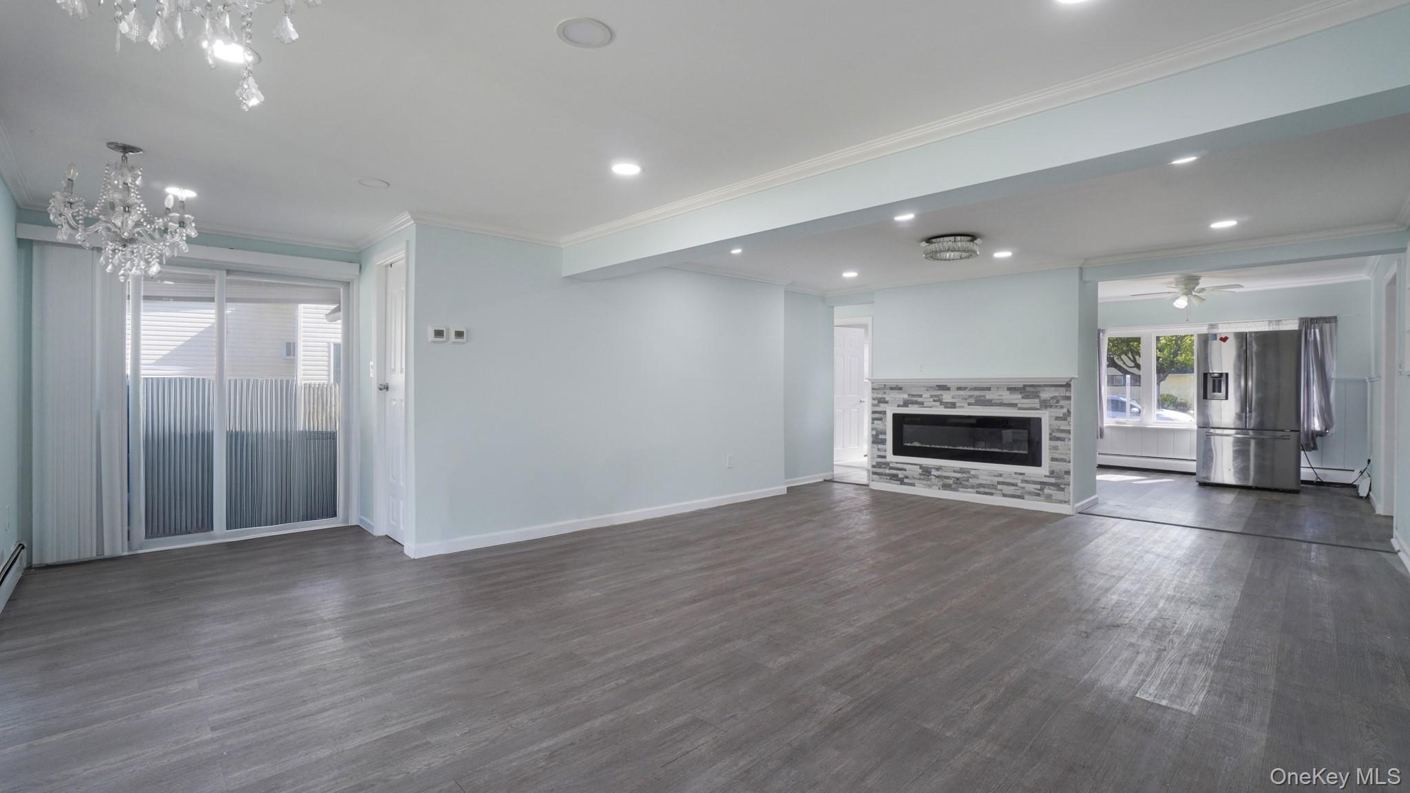 63 Blacksmith Road Levittown, NY 11756 - Photo 11 of 25 Spacious room featuring wood-finish flooring, a built-in electric fireplace with stone surround, recessed lighting, and a sliding glass door
