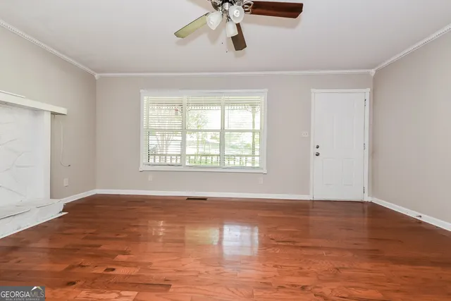 a view of an empty room with wooden floor and a window