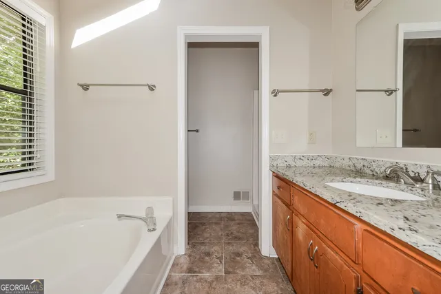 a bathroom with a granite countertop sink a mirror and a bathtub