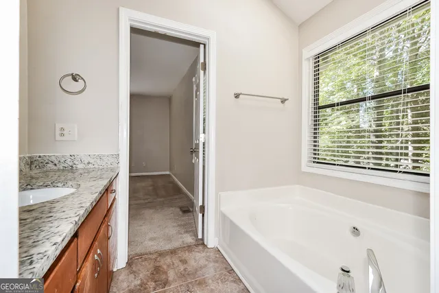 a bathroom with a granite countertop tub sink and mirror