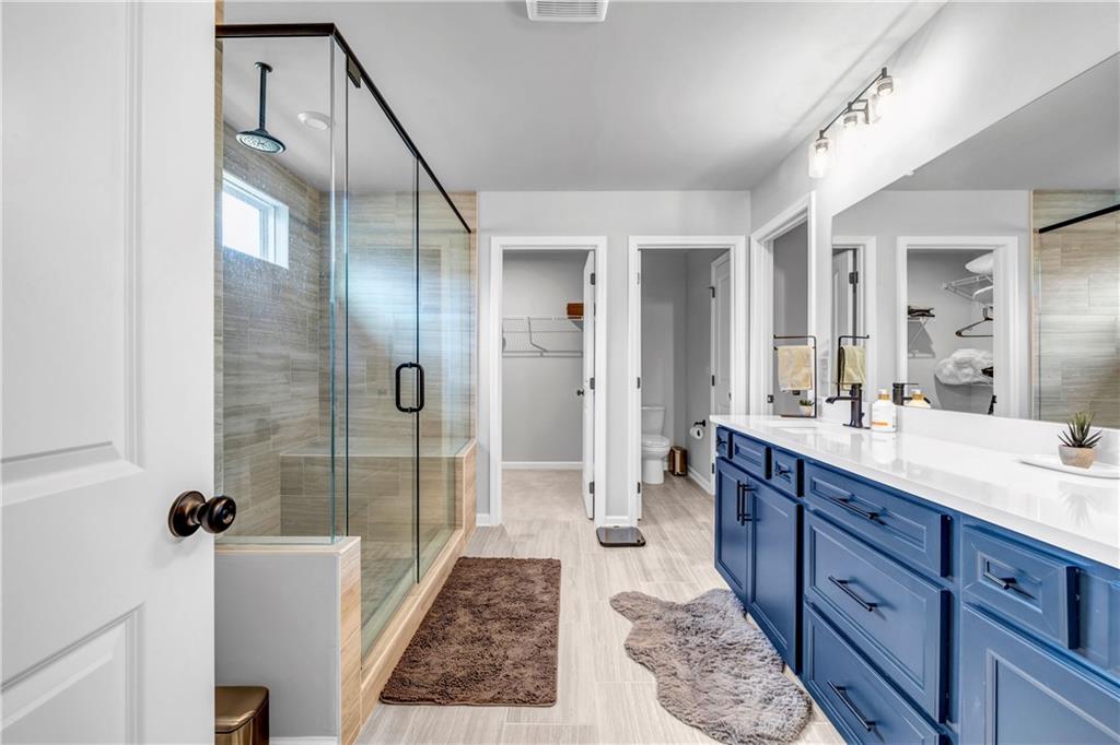 6095 Marigold Way Atlanta, GA 30349 - Photo 12 of 17 a bathroom with a double vanity sink a toilet a mirror and shower