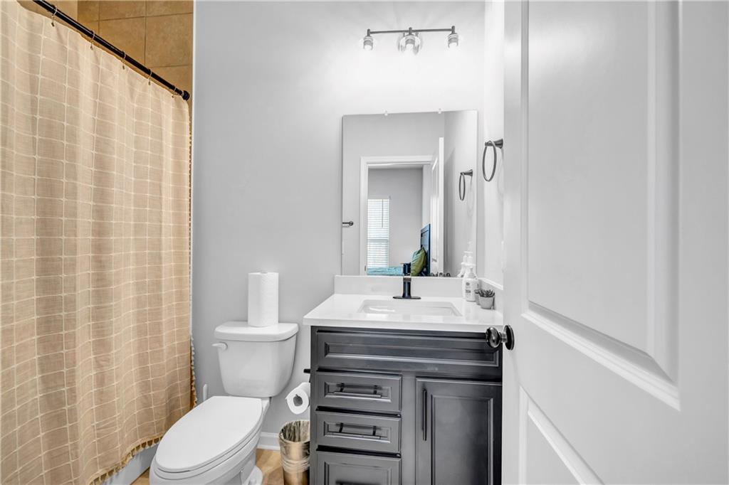 6095 Marigold Way Atlanta, GA 30349 - Photo 14 of 17 a bathroom with a sink a toilet a mirror and shower curtain