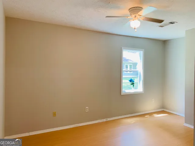an empty room with a window and a fan