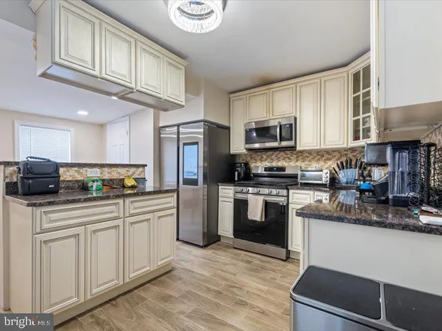 a kitchen with stainless steel appliances granite countertop a refrigerator a stove top oven a sink and dishwasher