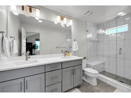 a bathroom with a double vanity sink toilet and shower