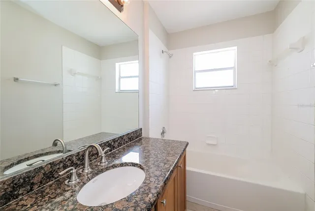 a bathroom with a granite countertop sink a mirror and a bathtub