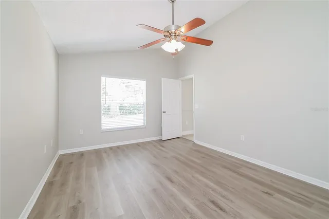 an empty room with wooden floor fan and windows