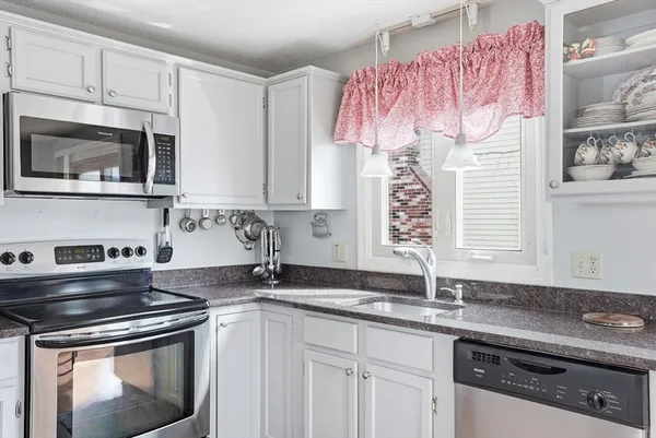 a kitchen with stainless steel appliances granite countertop a sink stove a refrigerator and a granite counter tops with wooden floors