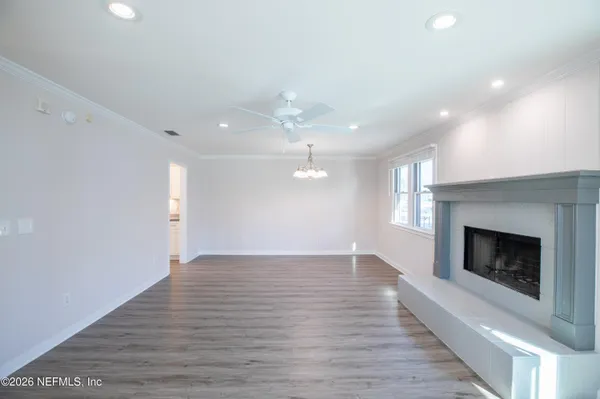 an empty room with wooden floor fireplace and windows