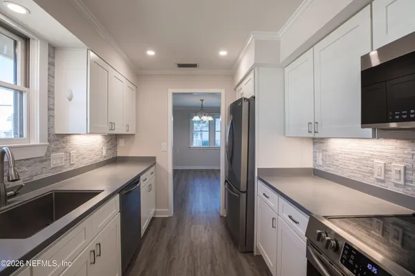 a kitchen with granite countertop a refrigerator stove and microwave