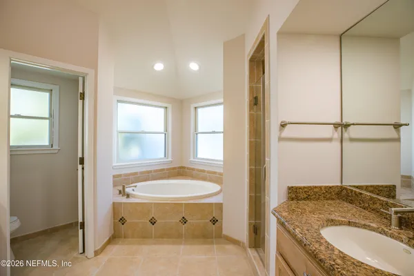 a bathroom with a granite countertop sink a toilet and shower