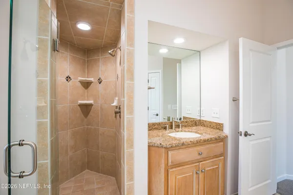 a bathroom with a granite countertop sink a toilet a mirror and window